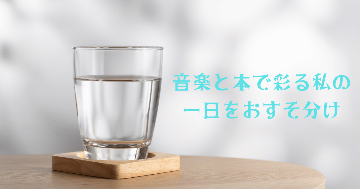 木製のテーブルに置かれた木製コースターの上に、透明なグラスに注がれた水が映り、背景に柔らかな光が広がる画像。グラスの横に水色文字で『音楽と本で彩る私の一日をおすそ分け』と記載された、見出しのアイキャッチ画像。